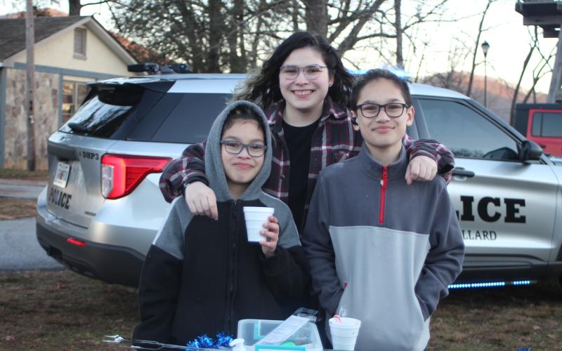 Megan Broome/The Clayton Tribune. Andres Torres, 10, left, Alexzandra Almanza, 20, and Cristian Torres, 13, enjoy hot chocolate and the Christmas lights and fun and games at the  “A Night Out in Christmastown” event held in Dillard Dec. 8.
