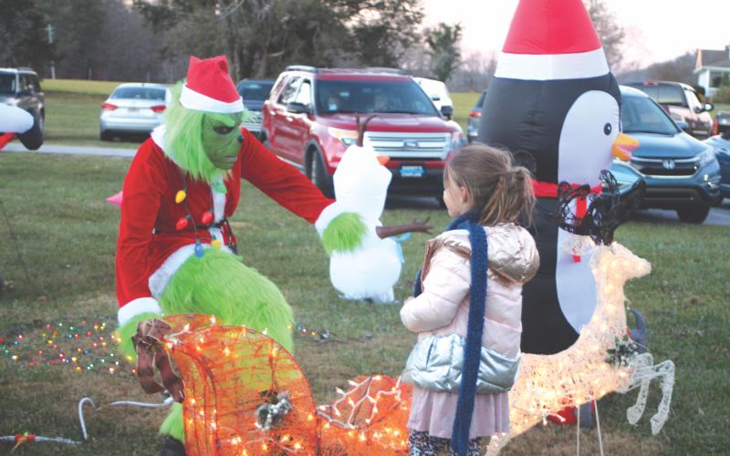 Megan Broome/The Clayton Tribune. The Grinch spreads Christmas cheer to Sawyer Crowe, 6, at the  “A Night Out in Christmastown” event held in Dillard Dec. 8.