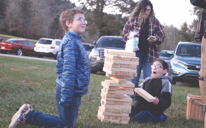 Megan Broome/The Clayton Tribune. Jacob Smith, 9, and Andres Torres, 10, play a game and enjoy Christmas lights and fun and games at the  “A Night Out in Christmastown” event held in Dillard Dec. 8. Also pictured is Alexzandra Almanza.