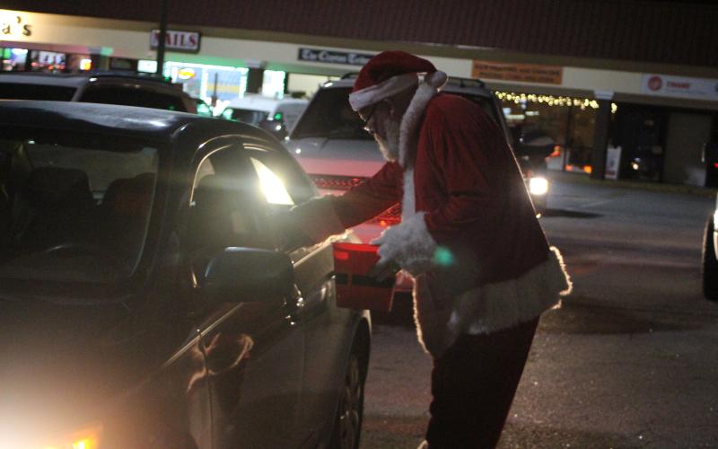 Megan Broome/The Clayton Tribune. Santa passes out candy and gifts to children at the Christmas toy drive held at the Food Bank of Northeast Georgia last Friday.