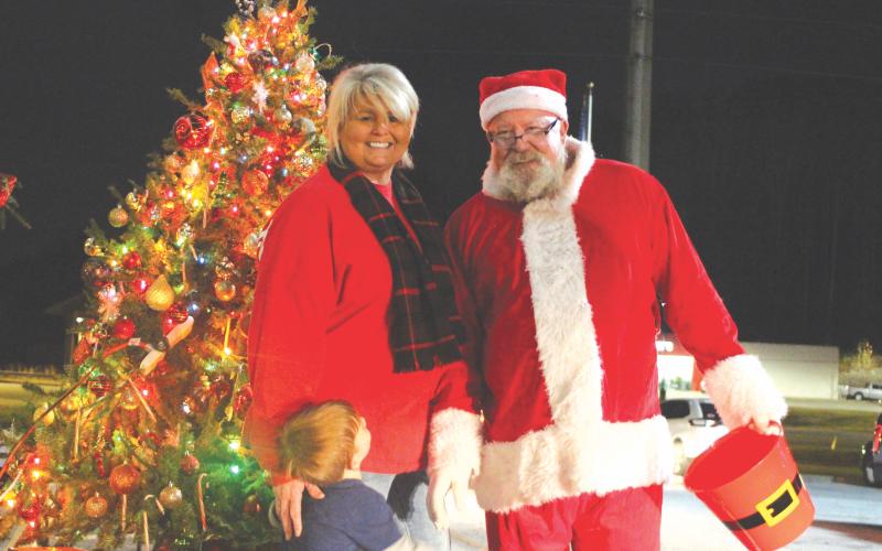 Megan Broome/The Clayton Tribune. Cissy Henry and her grandson Blaine Ancelet talk with Santa and help pass out gifts at the Christmas toy drive held at the Food Bank of Northeast Georgia last Friday.