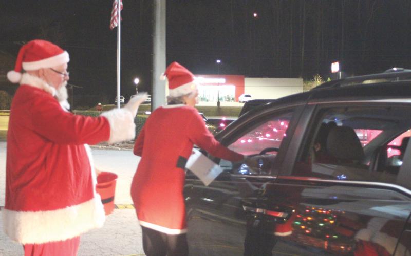 Megan Broome/The Clayton Tribune. Santa and Mrs. Claus wave at children in cars and pass out candy and presents at the Christmas toy drive held at the Food Bank of Northeast Georgia last Friday.