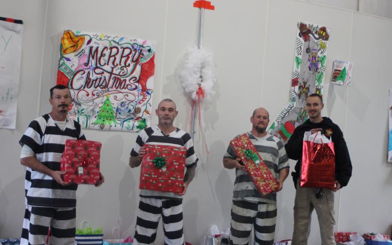 Megan Broome/The Clayton Tribune.  Rabun County Detention Center inmates Alvin Michael Watkins, Shannon Lee Watkins, and Shanan Glenn Britt and Transport Officer Steven Barnes help pass out gifts to children of inmates on Dec. 18. “It gives us hope in the community,” Watkins said about what the opportunity to give the gifts means to him.