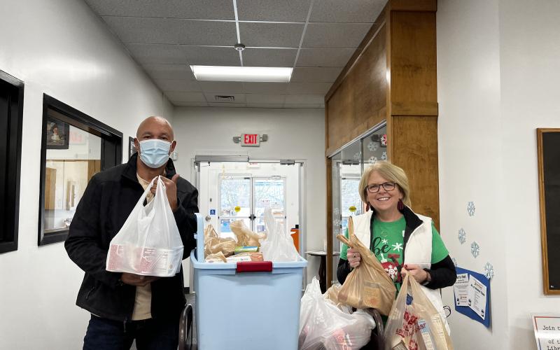 Rabun County Public Library. James Brim, manager of the Food Bank of Northeast Georgia Mountain Branch, left, receives a donation of food items from Kim Cannon, youth services, outreach and programming coordinator, collected from the Food for Fines program held by the library during December. Brim said 683 pounds of food were donated from the event.