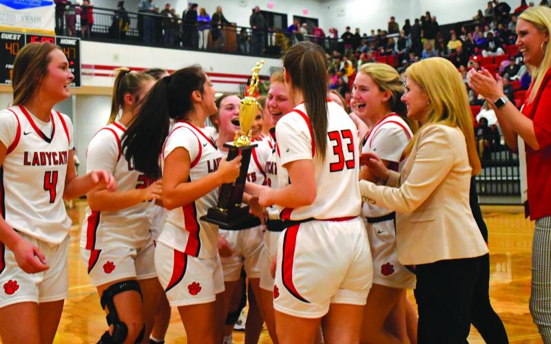 Enoch Autry/The Clayton Tribune. The Rabun County Ladycats celebrate with their region championship trophy they won on Feb. 18 with their defeat of Elbert County. The girls -- like the boys -- now are in the state AA tournament.