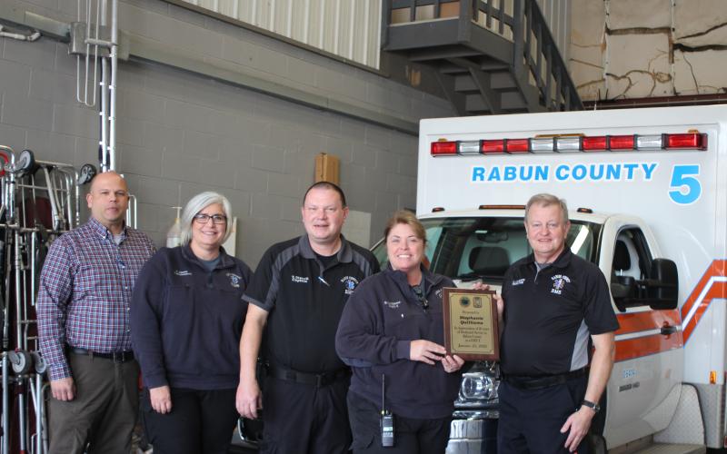 Megan Broome/The Clayton Tribune. Retiring EMT-I Stephanie Quilliams receives her honor from Mike Carnes, EMS/911 director (far right). Standing next to Quilliams, who retires with 26 years of service, are Lt. Brian Panell, Lt. Tammy Jones, and Capt. Trampes Stancil.