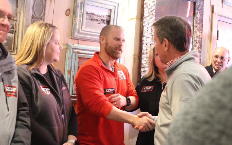 Megan Broome/The Clayton Tribune. Rabun County Schools Assistant Superintendent Matt Remillard shakes the hand of Georgia Gov. Brian Kemp on Feb. 18. Standing to the left of  Remillard is Kelly McKay, assistant superintendent inside the Clayton Cafe during Kemp’s visit. Also pictured is Alton Story.