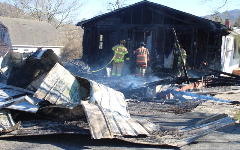 Megan Broome/The Clayton Tribune. Firefighters work to douse the remaining flames at a structure on Wolffork Church Road in Rabun Gap.
