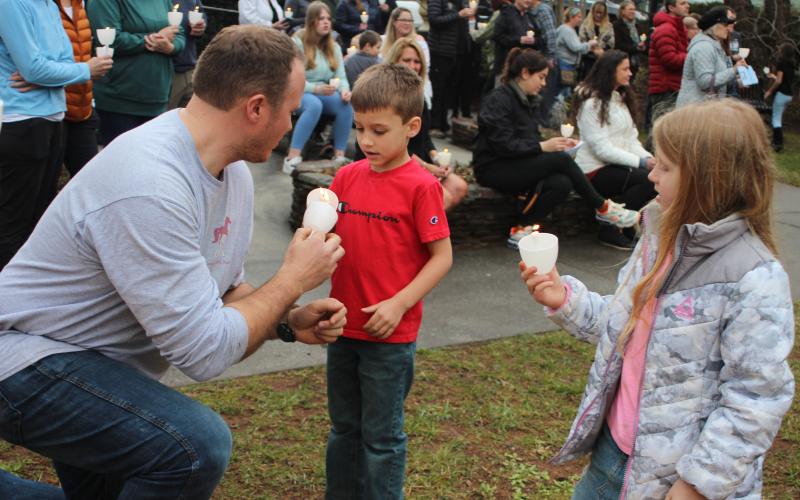 Megan Broome/The Clayton Tribune. Matt Pileski helps his children, Latham and Maggie Pileski, light candles at the candlelight service at The Rock House Feb. 22. A candlelight service and Mental Health March hosted by Georgia Mountain Psychological Associates were held to remember those who have lost their lives to mental illness.