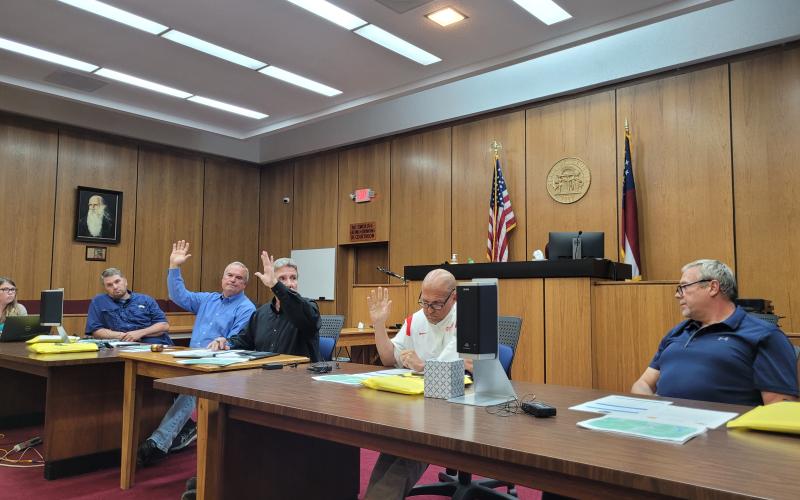 Megan Broome/The Clayton Tribune. A rezoning request for a 20.15 acre property off of Highway 76 East from Agricultural (A) to Commercial Business (CB) for the purpose of building storage units was denied by Commissioners in a 3-2 vote at Tuesday’s meeting. Kent Woerner, Greg James and Scott Crane show their hands in favor of the motion to deny the rezoning, while Will Nichols and Tom Garrison voted in opposition to the motion.