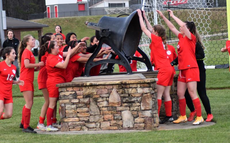 Enoch Autry/The Clayton Tribune. A smiling group of Ladycats ring the bell at the stadium after a 6-0 victory over the Lady Blue Devils.
