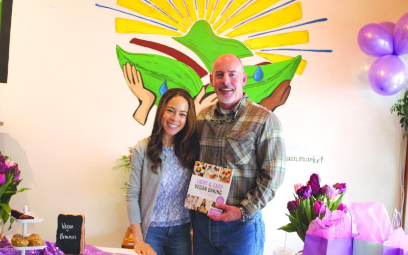 Megan Broome/The Clayton Tribune. Jillian Glenn, who has the blog “Peanut Butter &amp; Jilly,” poses with her father Roger Glenn at her book signing for her second title “Light &amp; Easy Vegan Baking,” held at the Holistic Mountain Market in Clayton on April 16.  Her first book “Easy Low Cal Vegan Eats” has recipes for every meal of the day.