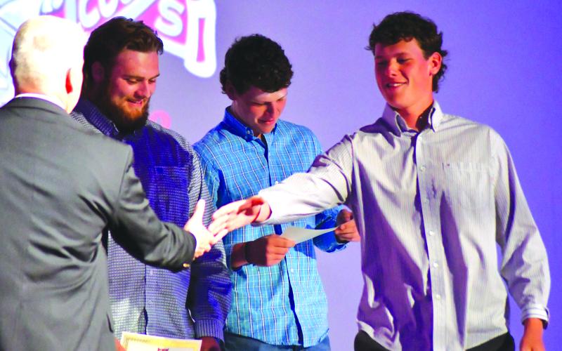 Enoch Autry/The Clayton Tribune. With his twin brother Conner Horton in the background, Garrett Horton receives his senior honors night recognition Tuesday as the Hortons were honored by RCHS athletic director Jason Gibson for signing golf scholarships to play at the University of North Georgia.
