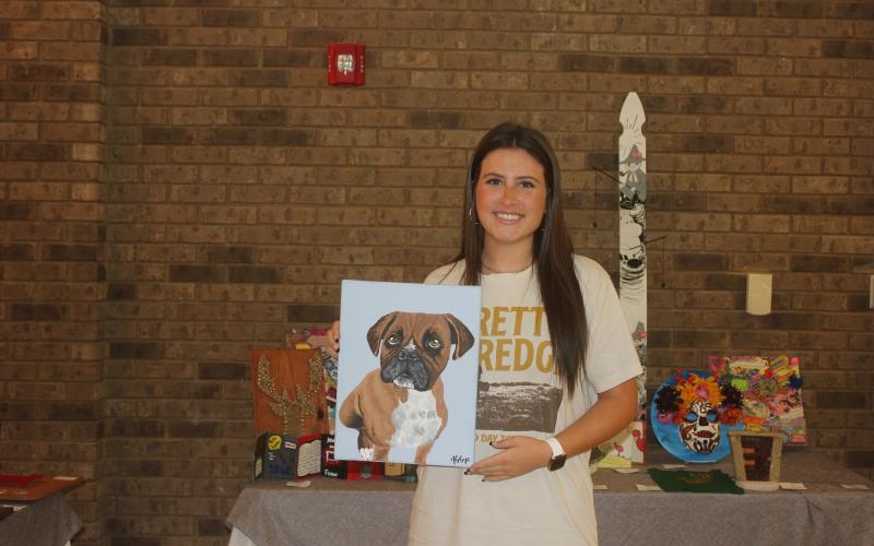 Megan Broome/The Clayton Tribune. RCHS upcoming senior Abbye Carver holds up her painting titled “Stella” at the RCHS Student Art Show held in the Fine Arts Building May 13. The medium is acrylic paint.