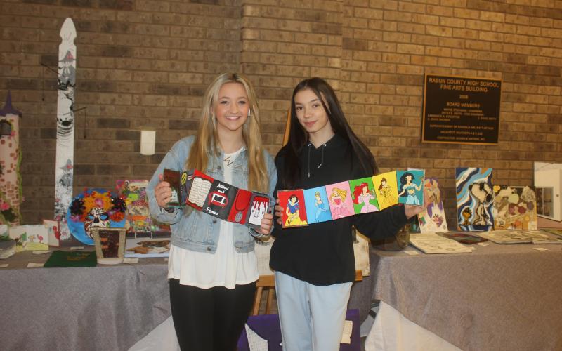 Megan Broome/The Clayton Tribune. Ninth grader Madilyn Gipson displays her artwork titled “Vampire Diaries” in the medium acrylic paint and Senior Jade Griffin displayed her artwork titled “Disney Princesses” in the medium of mixed media at the RCHS Student Art Show held in the Fine Arts Building at Rabun County High School May 13.