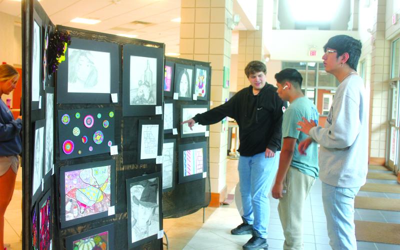 Megan Broome/The Clayton Tribune. Seniors Kane Collins, Ishy Duran and George Juarez browse the Rabun County High School Student Art Show held in the Fine Arts Building May 13. The show featured artwork from students in grades 9-12.
