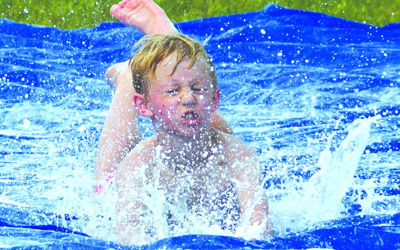 Enoch Autry/The Clayton Tribune. With some of the hottest days this year statewide, Rabun County outdoor summer youth camps have been challenged in finding ways to keep participants cool. Here, Cowen Gilbert, does a head-first slide on a tarp soaked with water and dish detergent during the last day of the Wildcat Baseball Camp on June 16.