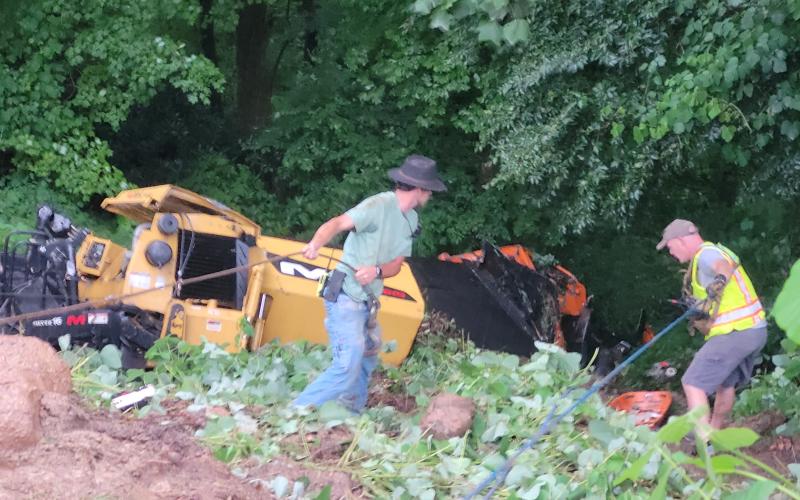 Megan Broome/The Clayton Tribune. Emergency responders work to remove a vehicle that overturned down an embankment while carrying work equipment on Highway 246 around Winding Ridge Drive in Rabun County June 17.