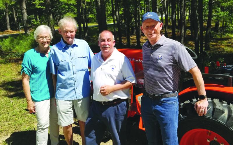 Submitted photo. Event organizer Kathy Booker, donor Steve Raebel, Victory Home Director Mark Beach, and donor Mike Hammer stand beside the new tractor that was purchased for Victory Home.
