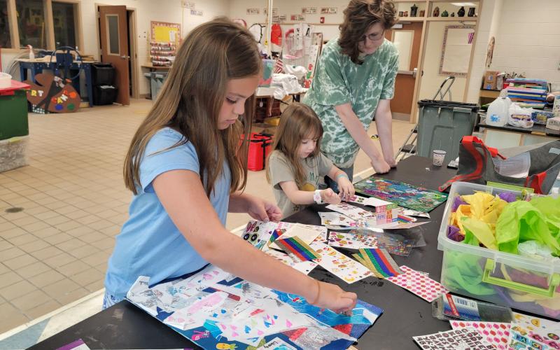 Megan Broome/The Clayton Tribune. Liberty Gregoire, 8, and Symphony Dowdall, 6, work with helper Kaylee Shirley on their art projects during Mrs. Jarrard’s Art Camp July 14.  Art Camp lasted several days last week.