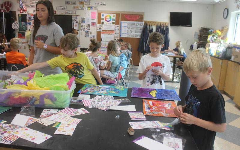 Megan Broome/The Clayton Tribune. Oryan Holifield, 8, Ethan Rolader, 10, and Hayes Ward, 6, work with helper Abbye Carver during Mrs. Jarrard’s Art Camp last week.