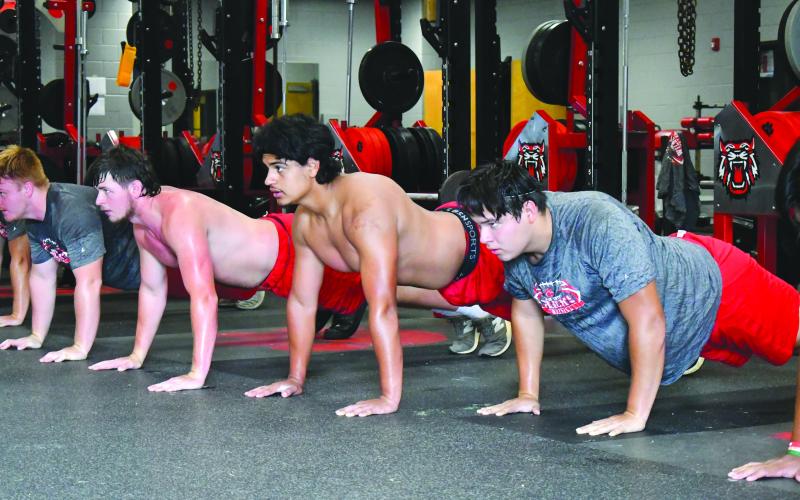 Enoch Autry/The Clayton Tribune. Wildcat football players do pushups as a team during their conditioning session at RCHS.