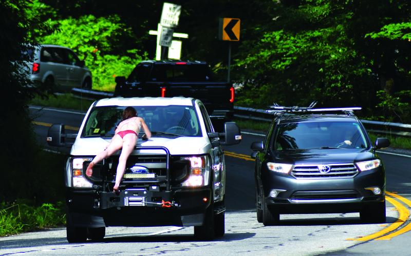 Enoch Autry/The Clayton Tribune. A female wearing only underwear lays on the hood of a Georgia Power pickup as the truck attempts to slow down on Highway 76 West for the safety of the woman. Sherry Sue Turpin was charged on June 29 by Rabun County Sheriff’s Office deputies with pedestrian under the influence of alcohol or drugs after witnesses say Turpin climbed off the hood to the truck. The incident caused stopped traffic in both directions.