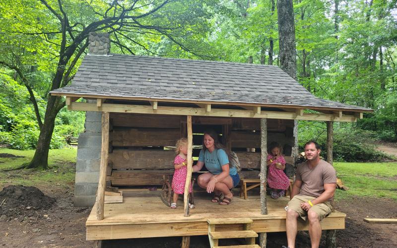 Megan Broome/The Clayton Tribune. Rose-Hannah Meeks and Clayton Meeks pose with with their children, Hadley, 2, and Maisie, 4, in the Children’s Village replica of the Savannah Cabin.