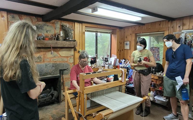 Megan Broome/The Clayton Tribune. Jamil Sewell, Sabrina Sewell and Isabella Sewell watch as Foxfire’s Kelly Coldren, Fiber Artist, demonstrates weaving at the Foxfire Museum last weekend.
