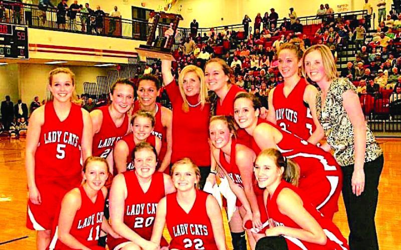 Submitted photo. The 2010-2011 Rabun County Lady Wildcats, with head coach Dee Dee Dillard holding the trophy aloft, celebrate winning the Region 8-AA basketball championship in front of their home fans.