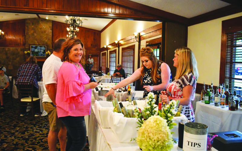 Megan Broome/The Clayton Tribune. Stacey Adams smiles as she enjoys the festivities at The Dillard House Labor Day event on Sept. 4. Ashley Cabe and Andria Robinson serve an assortment of wine and beer during the event, which featured a BBQ cookout and live music performed by Hunter Grayson.
