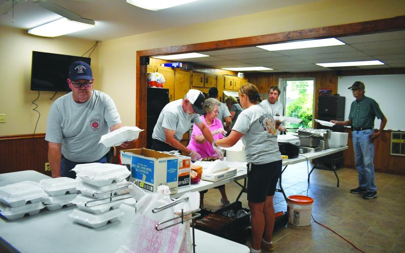Megan Broome/The Clayton Tribune.  Volunteer Firefighters serve BBQ to community members at the Station 12 Volunteer Fire Station BBQ fundraiser Sept. 24. Pictured in the forefront is volunteer Tim Wall. The department sold out completely as crowds of people turned out to support the cause. The fundraiser featured BBQ, raffles and live music from Jake McCracken.