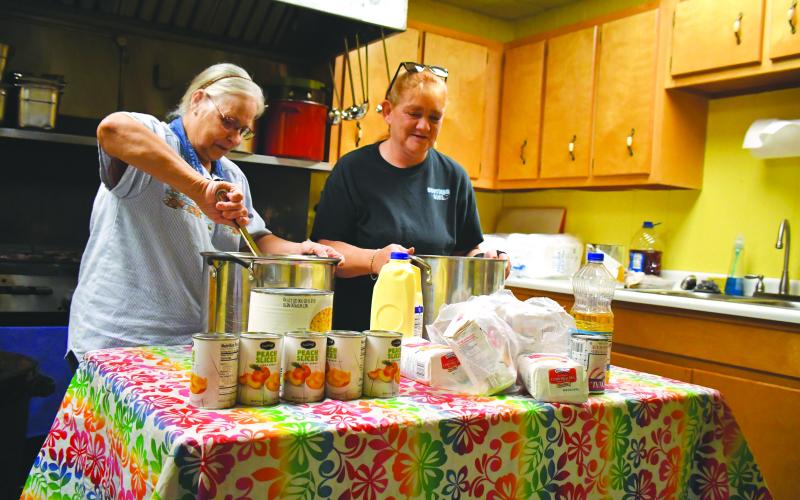 Megan Broome/The Clayton Tribune. Barbara Green and Amanda Chastain volunteer and prepare food for one of the food distributions and hot meals that are served at the American Legion Post 220 every Thursday.