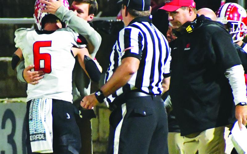 Luke Morey/The Clayton Tribune. Rabun County senior Jaden Gibson embraces passing coach Wes Holcombe after breaking two state records on Friday night.