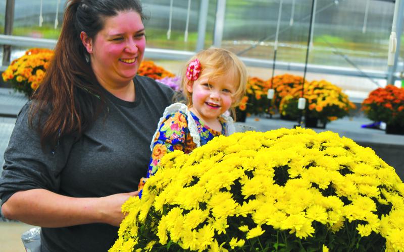 Enoch Autry/The Clayton Tribune. Two-year-old Davie Gantt and her mother Jennifer Gantt enjoy the greenhouse flowers at the new center.