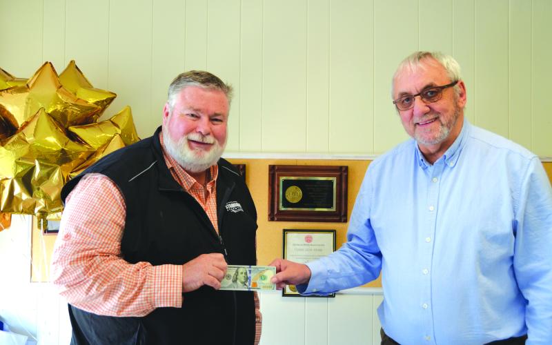 Linda Erbele/The White County News. Richard Clark (left) accepts $100 from Wayne Knuckles, The White County News publisher, for his photograph of colorful leaves. Clark’s photo was chosen for the cover of the fall 2022 edition of The Mountain Traveler which can be found in Rabun and neighboring counties.