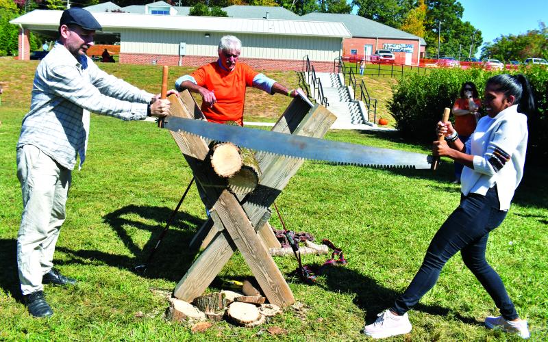 Megan Broome/The Clayton Tribune. Vladimir Kasperovich and Gabriella Pillay work on log-sawing at the Foxfire Mountaineer Festival.