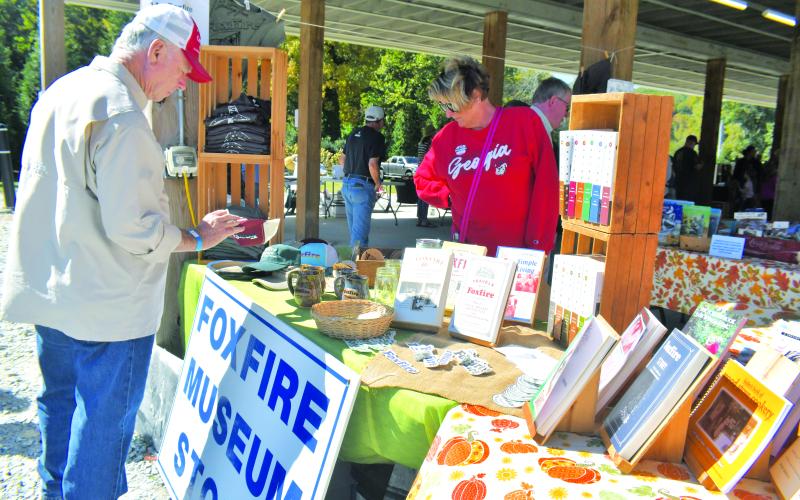 Megan Broome/The Clayton Tribune. Anne and Butch Bryant check out the Foxfire booth at the Foxfire Mountaineer Festival.