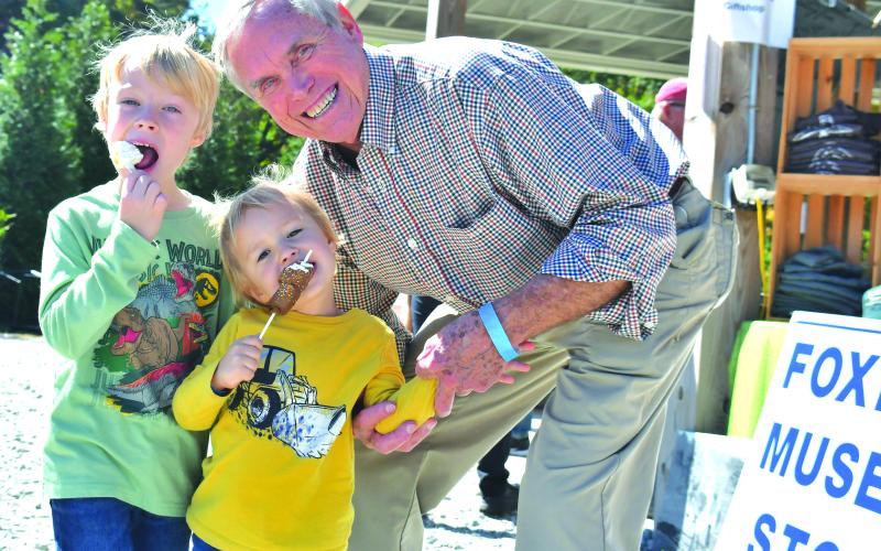 Megan Broome/The Clayton Tribune. Luke, 6, and Simon, 3, enjoy their ice creams and festivities at the Foxfire Mountaineer Festival with grandfather Elbert Bowles last Saturday.