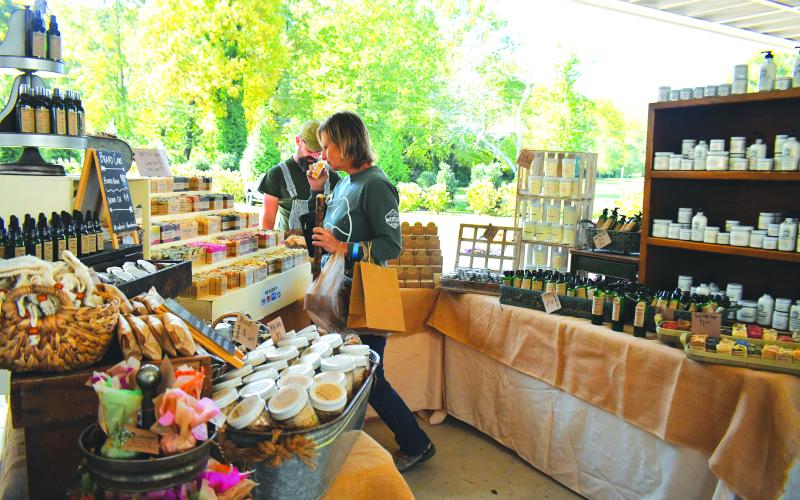 Megan Broome/The Clayton Tribune. Clayton City Manager Trudy Crunkleton checks out handmade soaps at the Blackberry Farmstead booth with Richard Johnson at the Foxfire Mountaineer Festival.