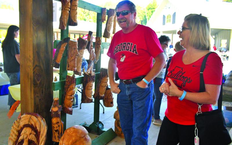 Megan Broome/The Clayton Tribune. R.B. Thrift and Shannon Fountain have a great time visiting all of the booths featured hand-crafter items at the Mountaineer Festival.