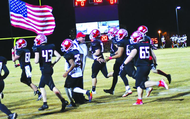 Enoch Autry/The Clayton Tribune. The Wildcats run out onto the field to start the game on Veterans Day as head coach Michael Davis slaps hands with his players.