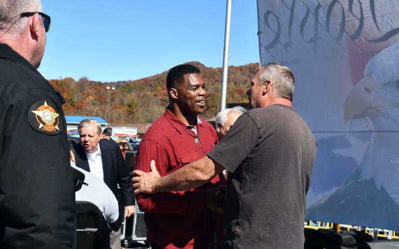 Megan Broome/The Clayton Tribune. U.S. Senate candidate Herschel Walker shakes the hand of Rabun County Commissioner Tom Garrison at the Oct. 26 rally held in Dillard. Also pictured is Rabun County Sheriff Chad Nichols.