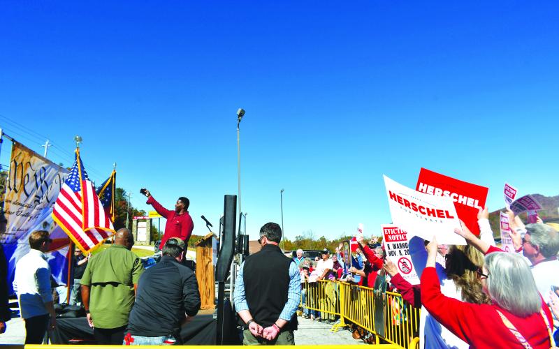 Megan Broome/The Clayton Tribune. On his visit to Rabun County, U.S. Senate candidate Herschel Walker takes a selfie with a gathering of attendees holding up campaign signs for the former football standout turned candidate. Walker faces Democratic incumbent Rev. Raphael Warnock in one of the most highly watched races in the nation.
