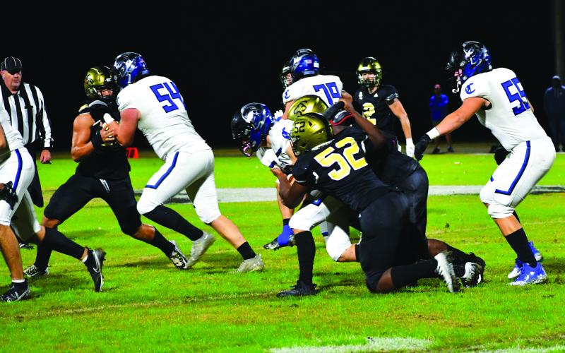 Luke Morey/The Clayton Tribune. Juniors Terry Ezeala and Gideon Herbert combine to take down senior quarterback Cameron Estep in the first quarter. Herbert had seven sacks  in the regular season.