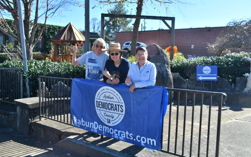Megan Broome/The Clayton Tribune. Rabun County Democrats Sandy Lipthrott, left, Susan Brewer, and Dee Daley give a thumbs up as Democrats set up campaign signs and mingle with voters at Veterans Memorial Park in downtown Clayton on Tuesday, Nov. 8.