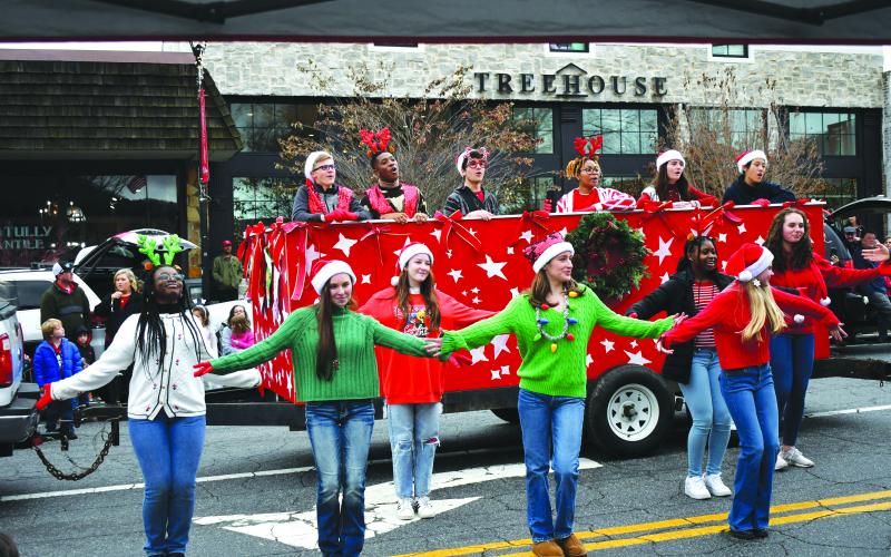 Enoch Autry/The Clayton Tribune. Rabun Gap-Nacoochee School students sing and dance to Christmas music at the annual Clayton downtown parade on on Main Street on Dec. 3. Singing from the float (from left) are Tyler Price, Chidera Onyia, Cyrus Manoogian, Sharra Rolle, Vivi Diaz and Vivian Guo. The dancers (from left) are Blaire Lauder-Williams, Elizabeth Brenner, McKenna Bilbrey, Anni Geren, KayKay Justilien, Abigail Brenner and and Emma Jenkins.
