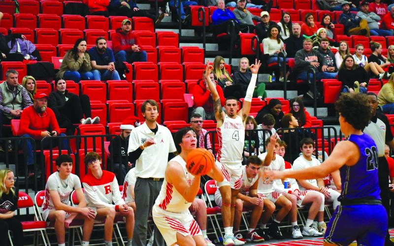 Luke Morey/The Clayton Tribune. With RCHS coach David Adcock watching and his WIldcat teammates rising up to signal a three, senior Jayton Henry knocks down a trey in the fourth quarter of the game against Walhalla.