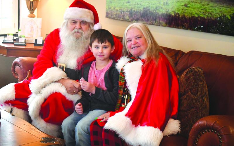 Megan Broome/The Clayton Tribune. Santa and Mrs. Claus took a break from Christmas preparations at the North Pole to visit with children in Rabun County Monday. The cheerful duo was spotted at Better Homes and Gardens Real Estate Metro Brokers in Clayton. The business was decorated with Christmas cheer and Santa and Mrs. Claus passed out cookies and candy canes to children. Pictured is 6-year-old Jace Shirley who is excited to meet Santa and Mrs. Claus.