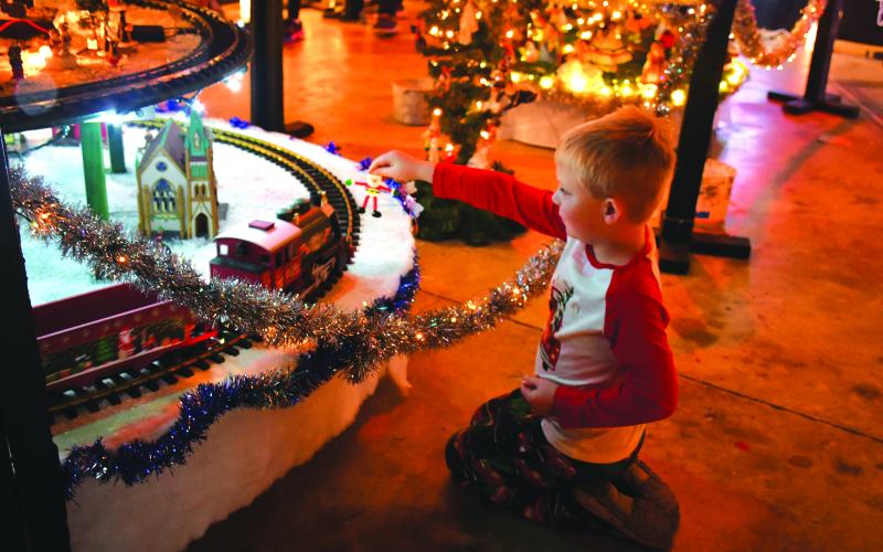 Megan Broome/The Clayton Tribune. Chance Epps, 4, plays with his Santa toy and a train at FAITH’s Christmas Village of Lights display.